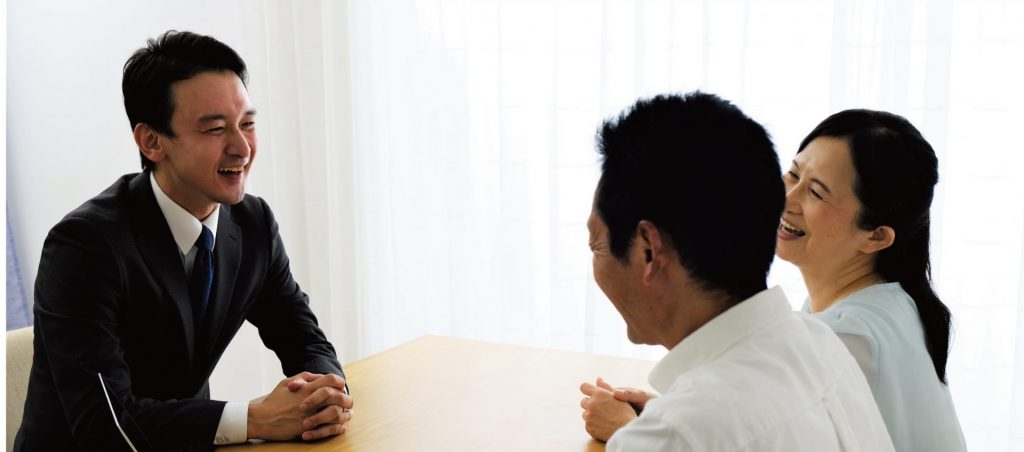 柏市で信頼できる不動産会社の担当者と相談する夫婦。土地購入や投資に安心感を与える仲介サポートのイメージ。