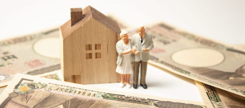 柏市の相続不動産を象徴する家と高齢夫婦のフィギュア。価格相場や資産価値を把握するためのイメージ。