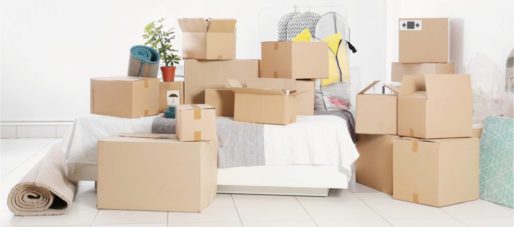 リフォーム中の仮住まい準備をイメージした室内の写真。ベッドの上や周囲に積まれた段ボールが引っ越しや荷物整理の様子を示し、工事期間中の生活環境の変化を象徴している。