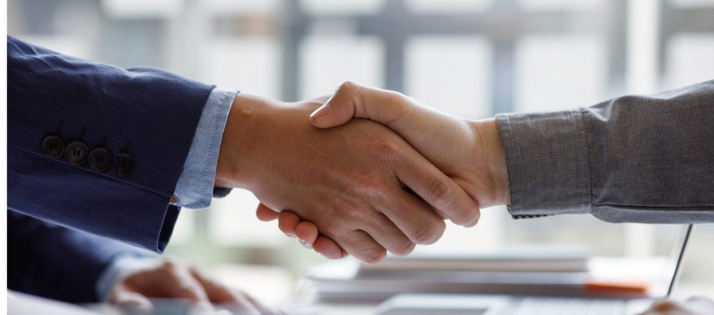 柏の管理会社とオーナーが契約に合意し、握手を交わす場面