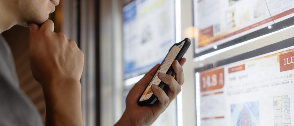 不動産情報をスマホで確認する男性の様子。我孫子市で売買や賃貸を検討する際の物件情報チェックイメージ。