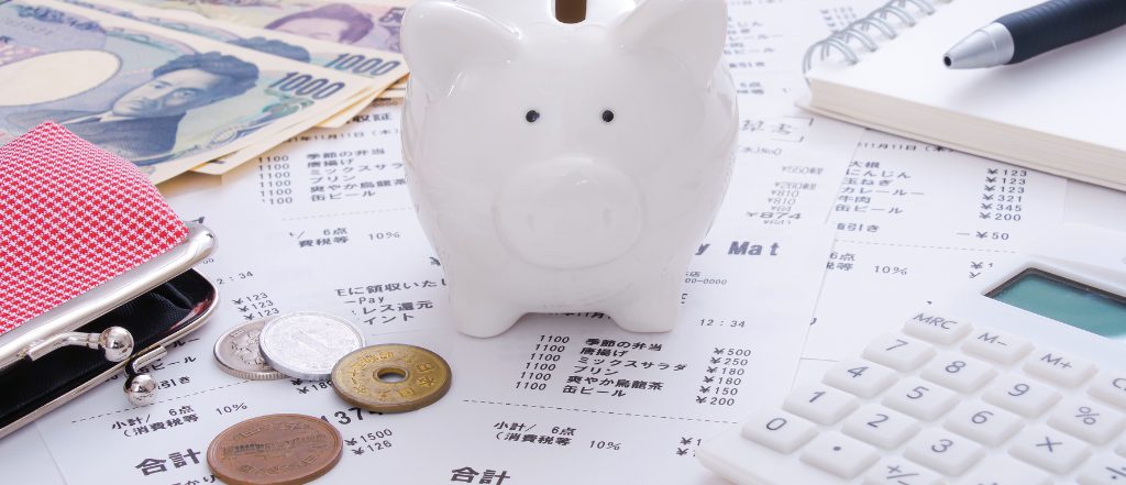 家計簿や電卓と貯金箱の写真。我孫子市の不動産売買や賃貸の相場を考える際の予算管理を表現するイメージ。